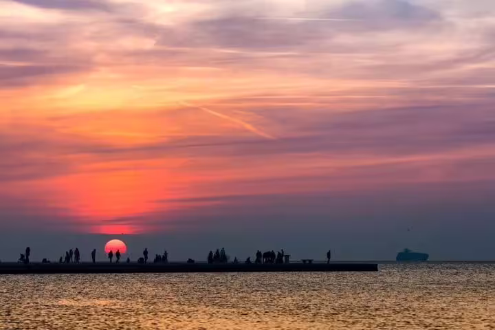 Travelers enjoy a colorful sunset over the Adriatic Sea from Trieste’s Molo Audace pier on a private walking tour