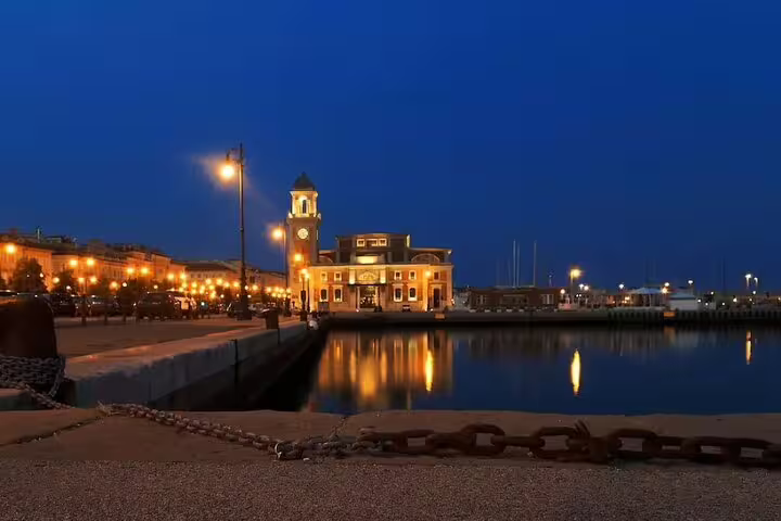 Trieste waterfront and clock tower glowing at dusk, seen from the harbor promenade on a private guided walking tour