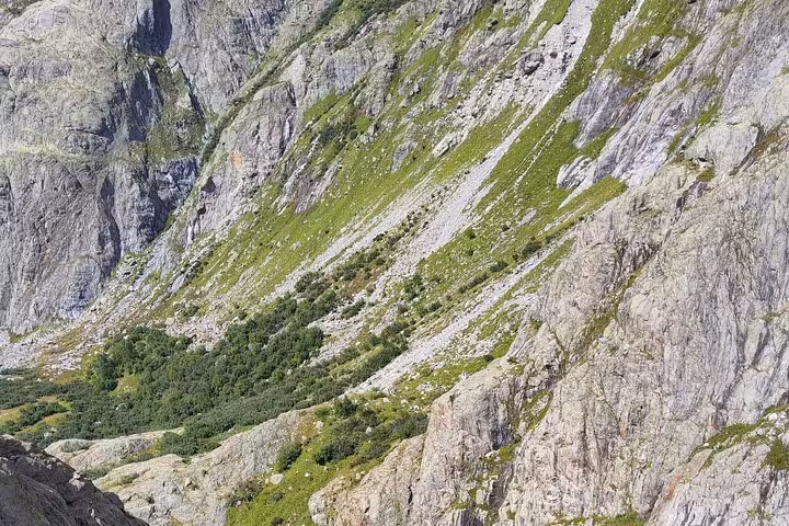 Rocky alpine slope and green meadows near Trift Suspension Bridge hike on a Zurich day trip, Switzerland