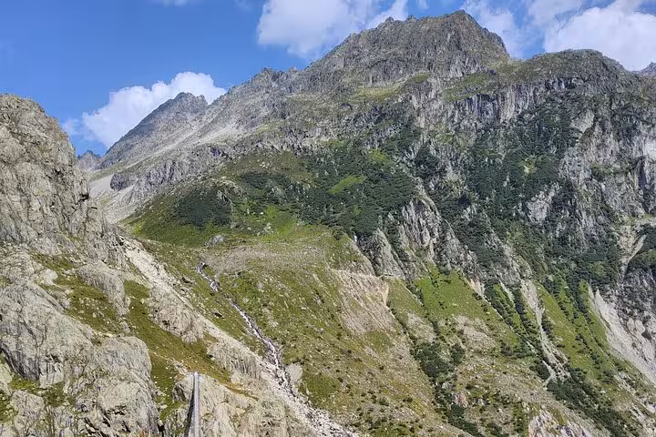 Swiss Alps panorama near Trift Suspension Bridge, scenic Zurich day trip with rugged peaks and green slopes