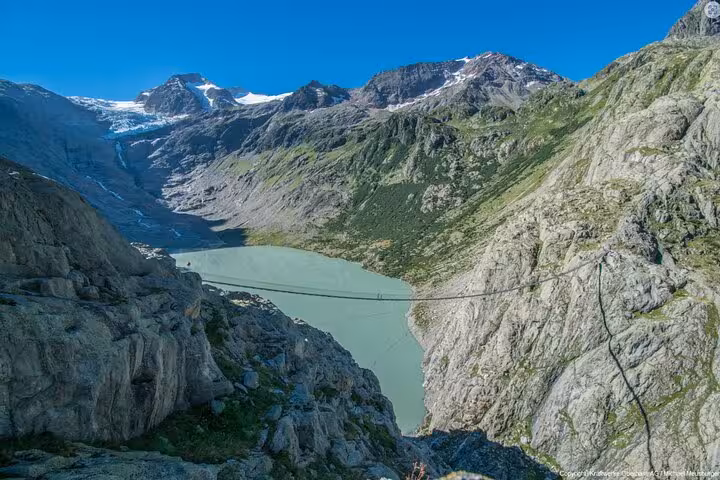 Trift Suspension Bridge above turquoise Triftsee lake, Swiss Alps hike on a Zurich day trip