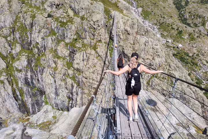 Traveler crossing Trift Suspension Bridge above rocky gorge, highlight hike on Zurich day trip to Swiss Alps