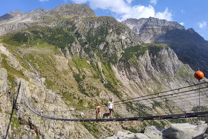 Travelers crossing the Trift Suspension Bridge in the Swiss Alps on a Zurich day trip hiking adventure
