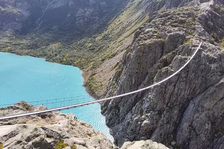 Trift Suspension Bridge above turquoise Triftsee, highlight of a Zurich day trip hike in the Swiss Alps