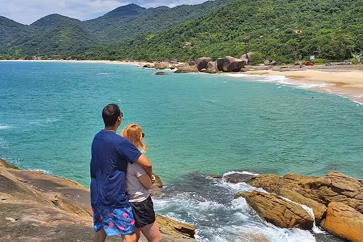 Couple admiring the turquoise waters and rocky shoreline of a secluded Trinidad beach, perfect for a romantic getaway.