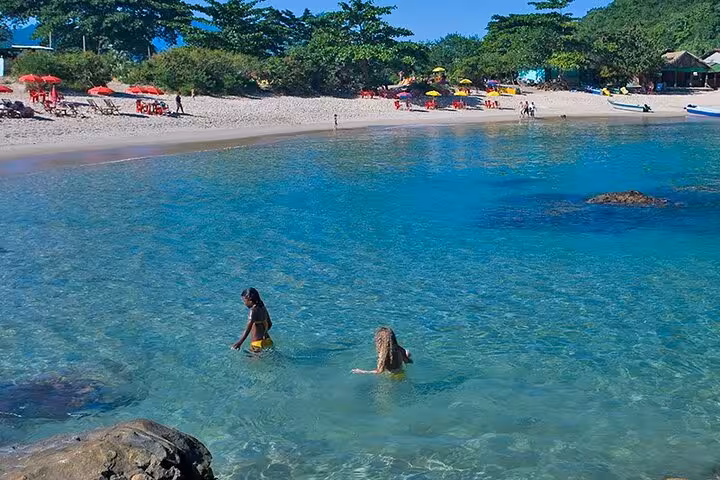 Visitors enjoying a swim in crystal-clear waters at a vibrant beach in Trinidad, featured in Paraty Tours' Nature & Sea package.