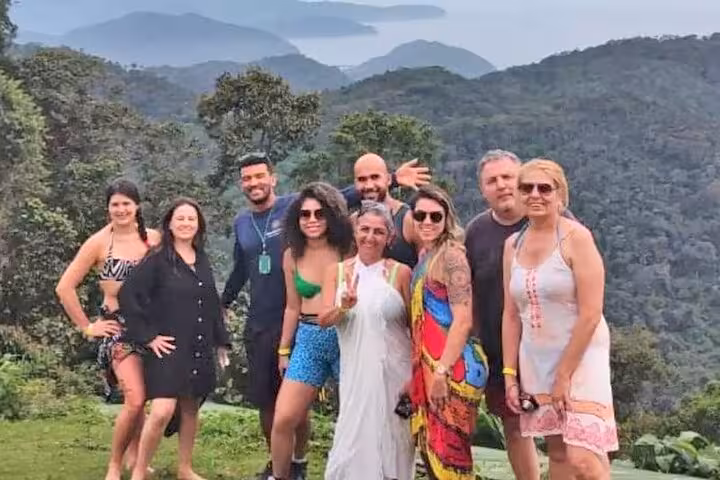 Group of tourists posing with scenic mountain and sea views in Trinidad, highlighting nature and adventure.