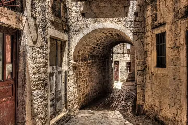 Narrow medieval stone alley with archway in Trogir Old Town, authentic sight on a private walking tour