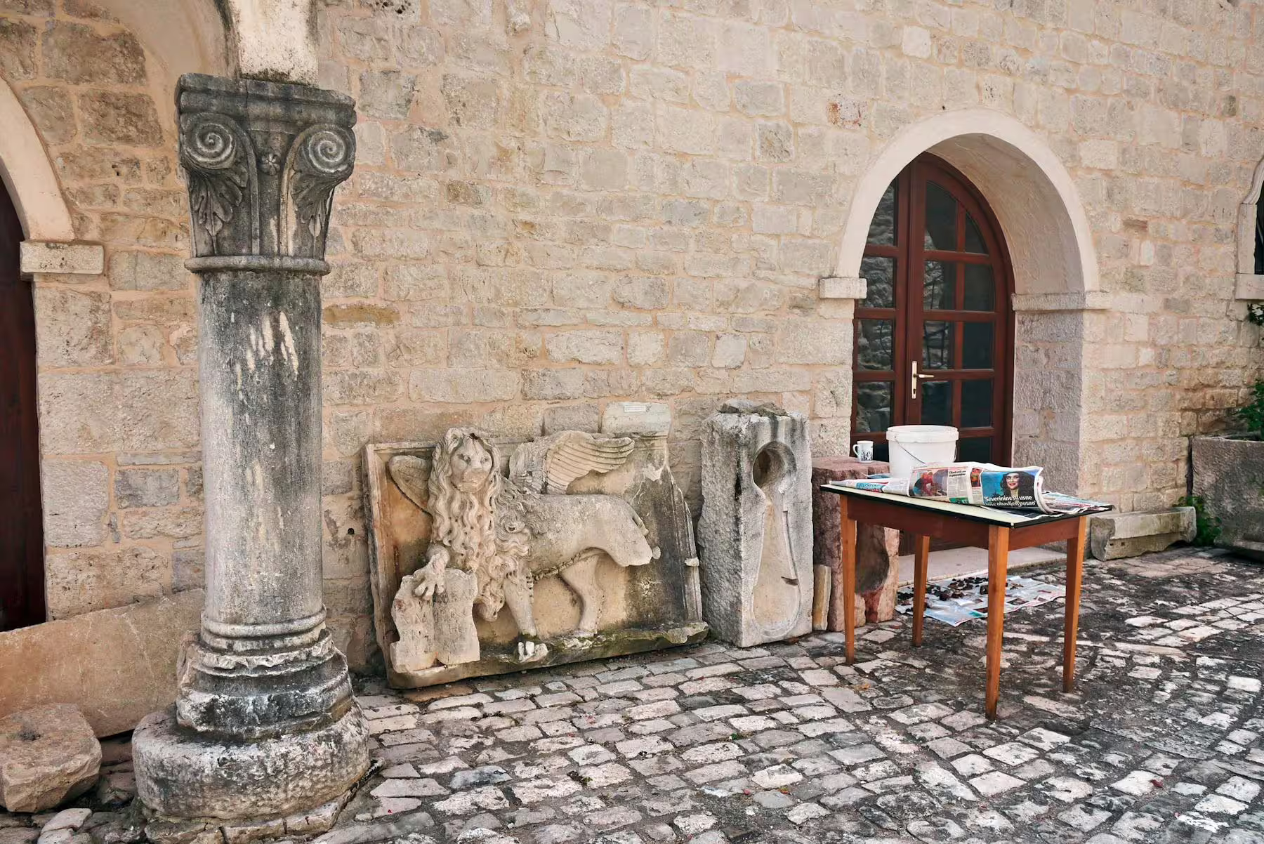 Historic stone courtyard with carved column and lion relief in Trogir old town on day trip from Makarska