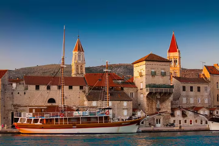 Trogir waterfront with traditional boat and medieval stone towers on private shore excursion from Split port