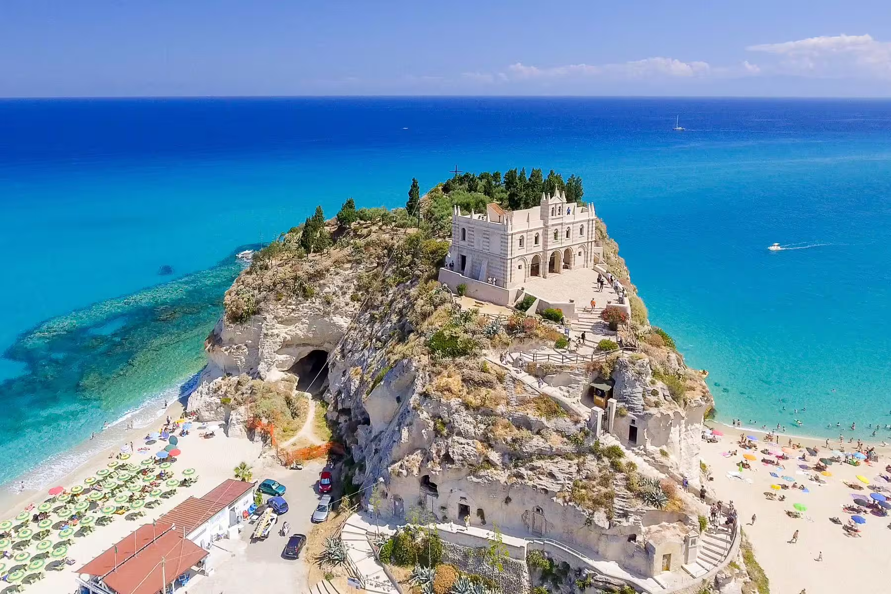 Aerial view of Tropea’s Santa Maria dell’Isola monastery on a rocky cliff above turquoise Tyrrhenian Sea beaches in Calabria