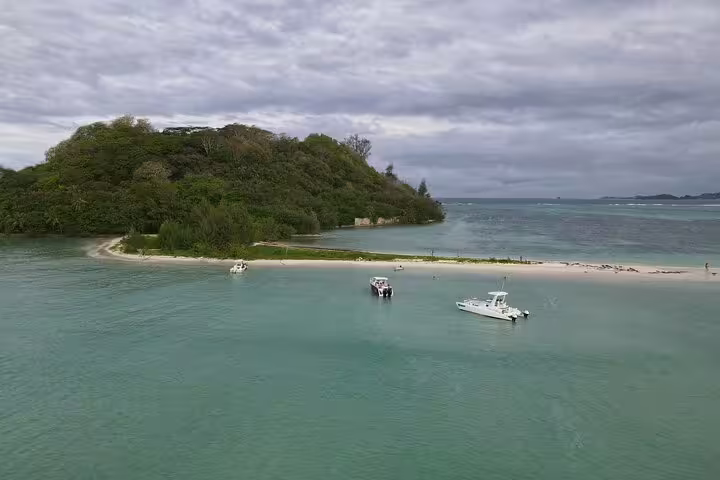 Scenic view of a tropical island with boats anchored on turquoise waters, perfect for a private snorkeling day trip.