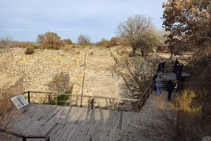 Ancient stone ruins and wooden walkway at Troy Archaeological Site on full-day tour from Istanbul with lunch