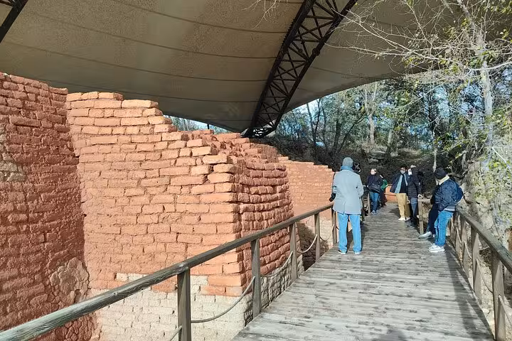 Visitors walking past preserved red brick ruins under canopy at Troy, part of full-day Istanbul Troy tour with lunch
