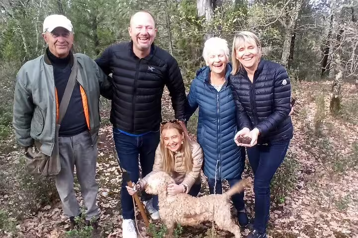 Happy group with local guide and truffle dog pose in Tuscan forest during truffle hunting tour with lunch and Chianti wine