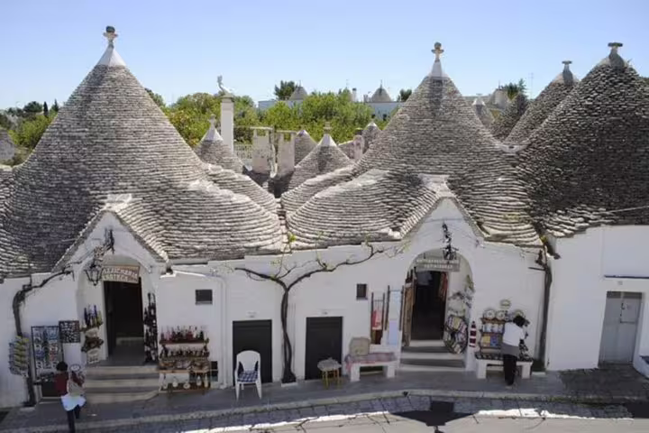 Row of conical-roof trulli souvenir shops in Alberobello’s historic center visited on a private tour from Naples