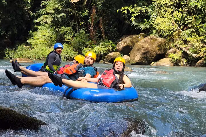Adventurous group enjoying tubing on the Celeste River, navigating gentle rapids amidst verdant rainforest.