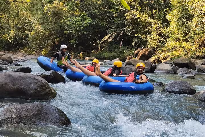 Group of thrill-seekers tubing down the lively rapids of the Celeste River, surrounded by lush tropical rainforest.