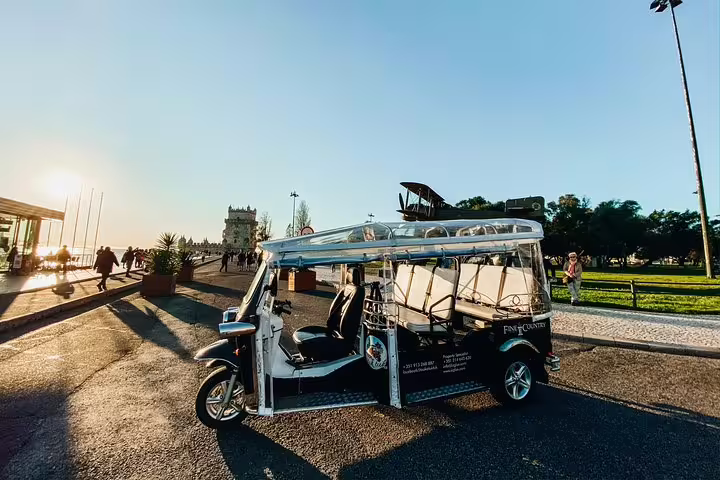Tuk Tuk parked near the iconic Belém Tower at sunset, perfect for exploring Lisbon's historic Belém District.