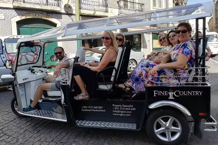 Tourists enjoying a scenic ride on a tuk-tuk through the charming streets of Belém, Lisbon.