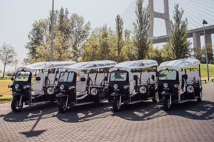 Fleet of tuk tuks parked near Lisbon's Vasco da Gama Bridge, ready for a scenic tour of the old town.