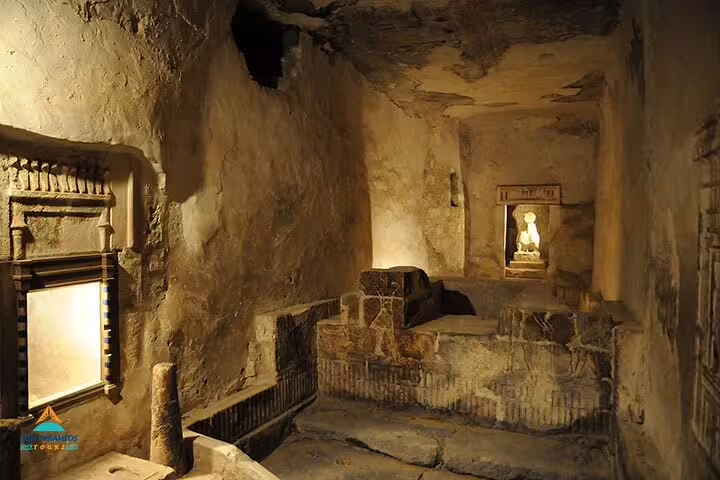 Rock-cut tomb chamber at Tuna El Gabal, El Minya, with carved niches and warm lighting on a private tour from Cairo