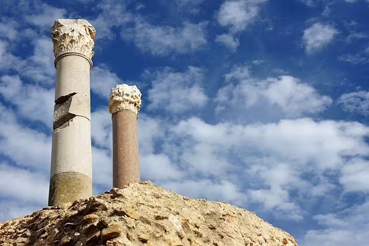 Ancient Roman columns reaching into a blue sky at Carthage archaeological site, showcasing Tunisia's historical heritage.