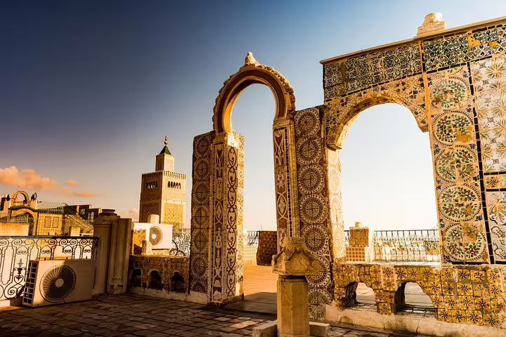 Explore Tunisia's architectural heritage with stunning tilework and arches under a bright sky on the discovery tour.