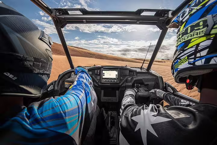 Two adventurers driving a buggy through the Tunisia Sahara desert under a clear blue sky on a thrilling safari tour.