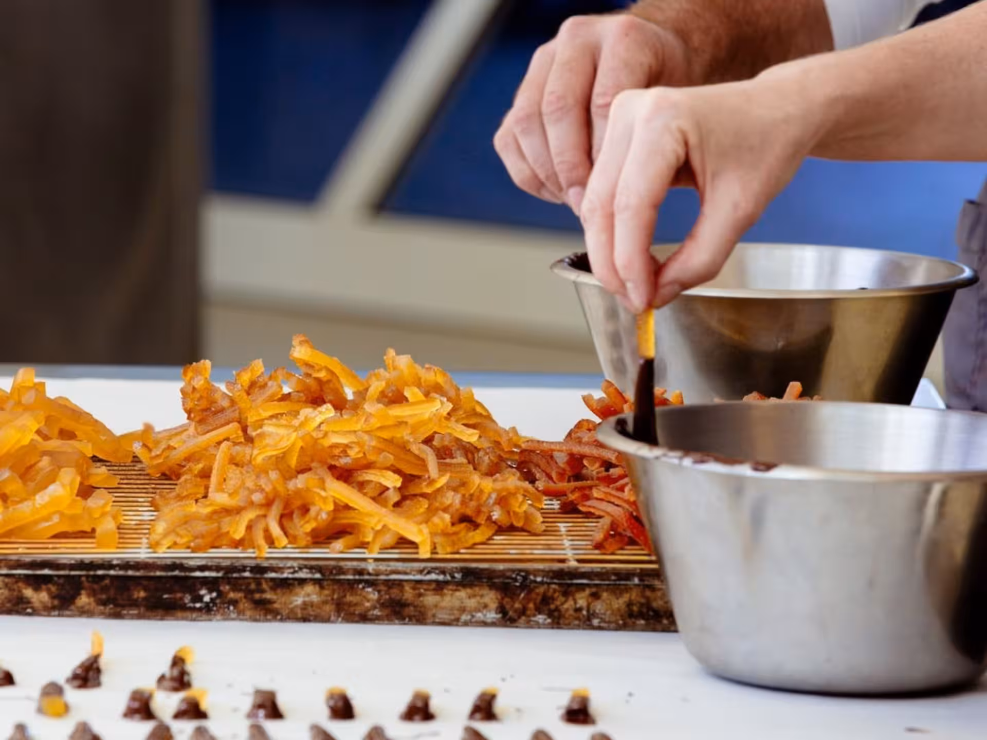 Candied fruits being dipped in chocolate at Turin Chocolate Factory, offering a glimpse of the guided tour's treats.