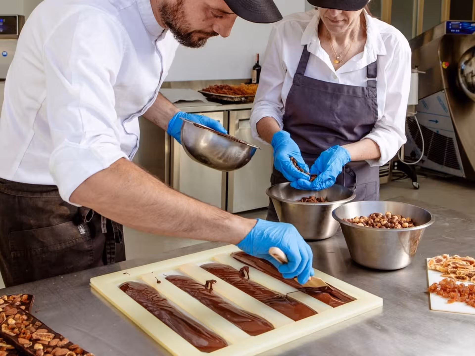 Chocolatier crafting artisanal chocolate bars with nuts during Turin Chocolate Factory tour.