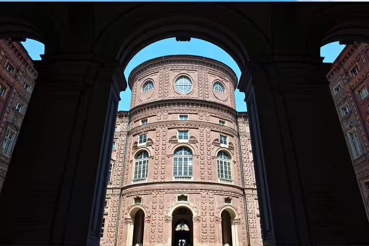 Self-guided Turin scavenger hunt view of Palazzo Carignano facade through archway, Baroque highlights tour