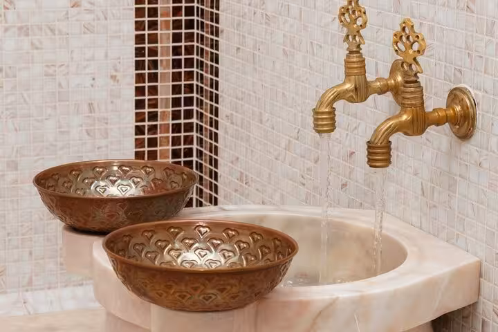 Brass taps and copper bowls at marble basin in Turkish bath, part of private Ephesus shore excursion
