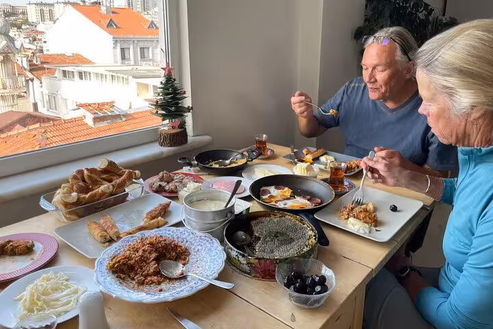 Guests enjoying a homemade Turkish breakfast spread by the window, tasting local dishes and tea with hosts