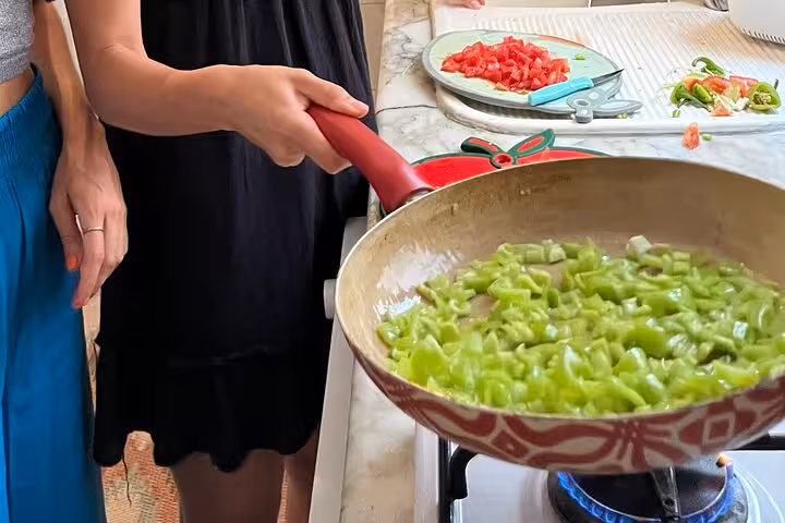 Local friends sauté green peppers on a gas stove for authentic homemade Turkish breakfast cooking class