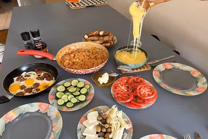 Homemade Turkish breakfast spread with menemen, sucuk eggs, olives and fresh cheese in a local home