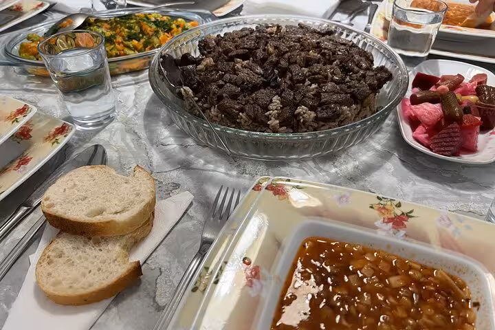 Close-up of homemade Turkish family dinner in Istanbul featuring beef pilaf, beans stew, salad, bread and pickles