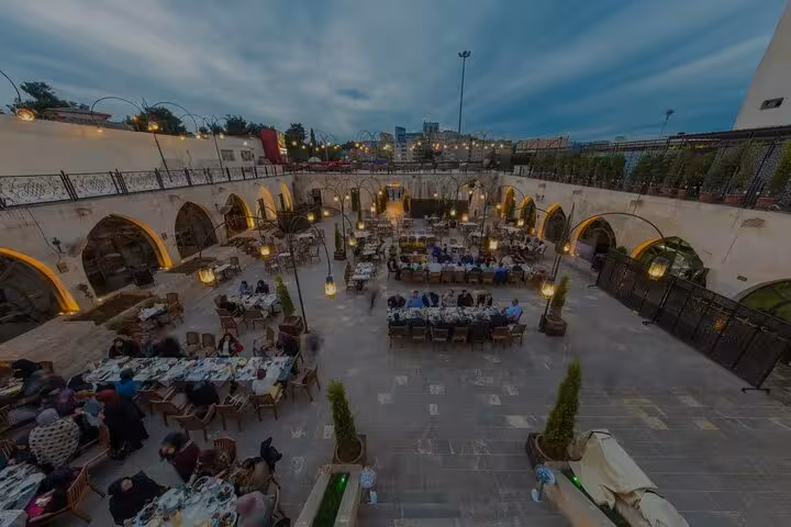 Night view of lively Turkish courtyard dinner venue with shared tables, part of Turkish gastronomy tour