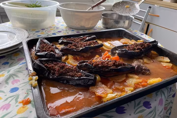 Freshly baked Turkish karniyarik stuffed eggplants in tomato sauce on tray at an Istanbul home cooking class
