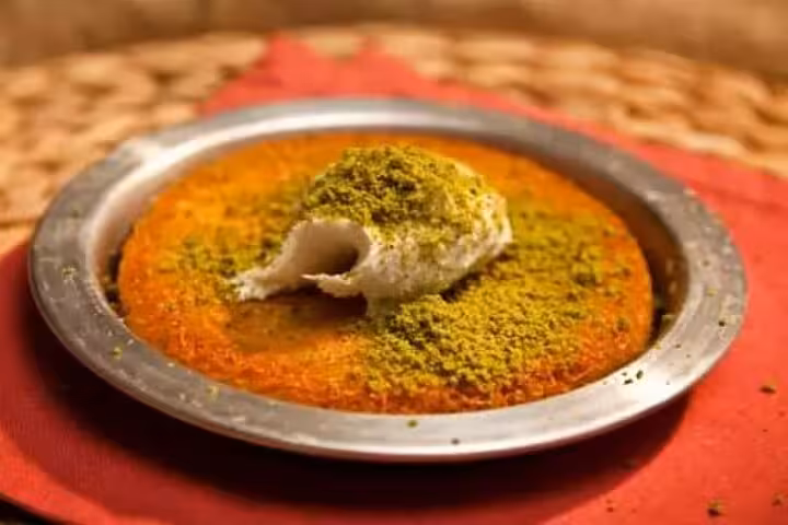 Traditional Turkish künefe dessert topped with pistachio and kaymak, served warm on a food tour stop