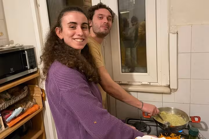 Guests cook Turkish meze in an Istanbul home kitchen, stirring a pan during beginner cooking class