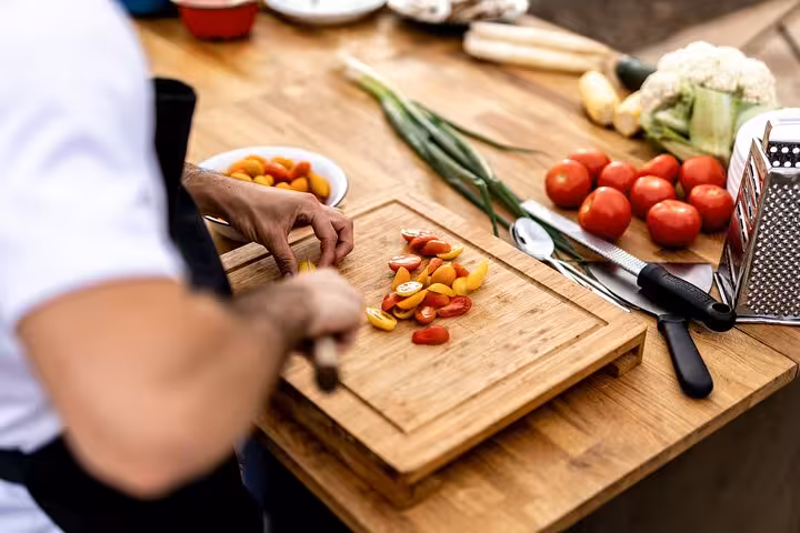 Chef slicing colorful tomatoes on a wooden board during a hands-on Tuscan cooking class in Rome.