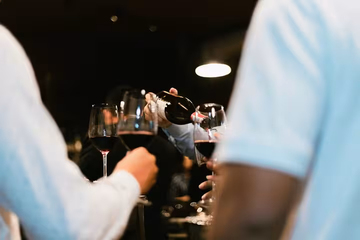 Guests enjoying a wine pouring experience during a Tuscan cooking class and wine tasting tour from Rome.