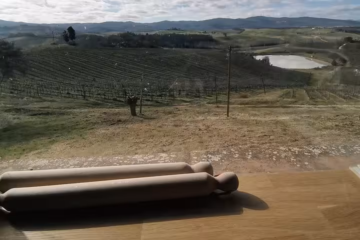 Rolling pin set against a panoramic view of Tuscan vineyards, perfect for a cooking class and wine tasting experience.