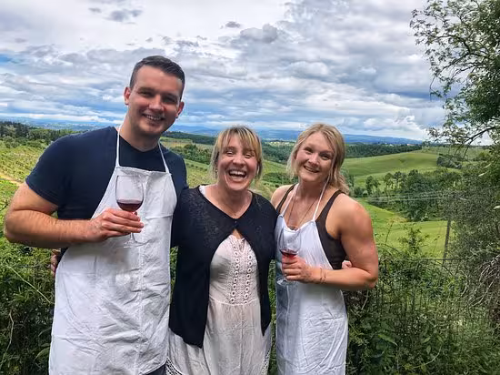 Guests enjoy wine and laughter at a Tuscan farmhouse cooking class with scenic views.