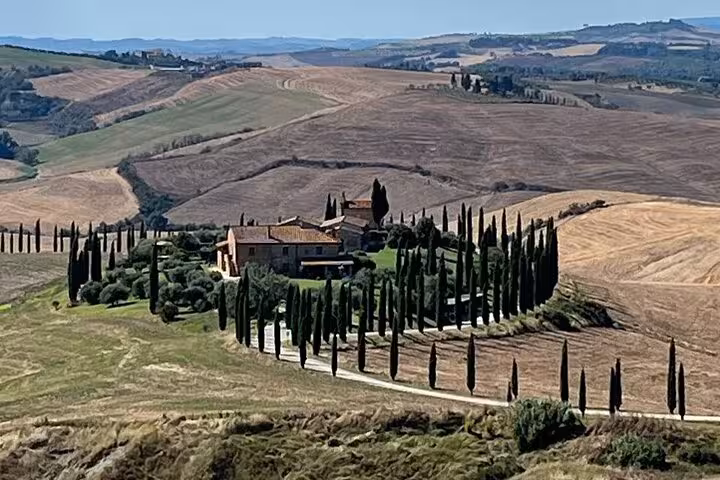 Charming Tuscan farmhouse surrounded by cypress trees amid the rolling hills of Val D'Orcia.