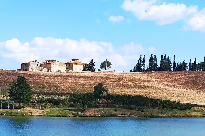Tuscan farmhouse near Volterra overlooking golden hills and cypress trees by a tranquil lake on a private San Gimignano tour