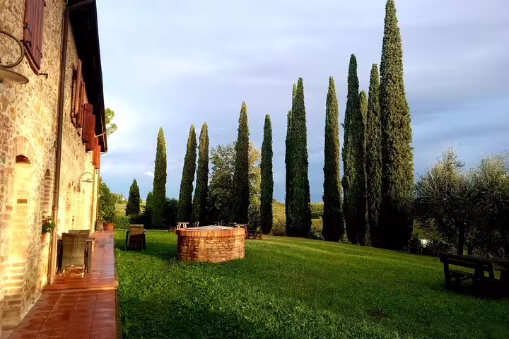 Stone farmhouse with terrace, lawn and tall cypress trees at a Tuscan winery on a Volterra and San Gimignano private tour