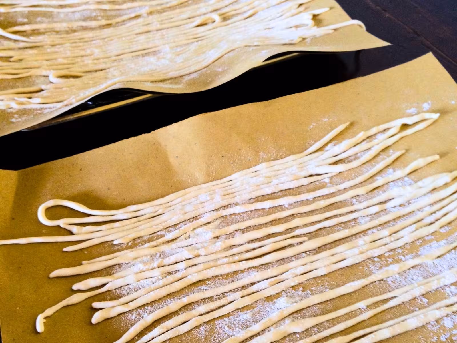 Freshly made pasta strands are laid out on parchment for drying in a Tuscan cooking class.