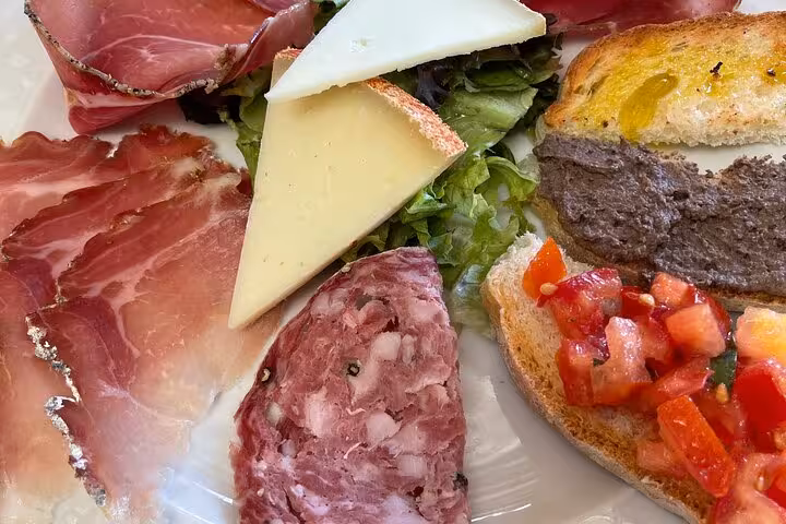 Delicious Tuscan platter with cured meats, cheese, and bruschetta served during the Tuscany tuk tuk tour.